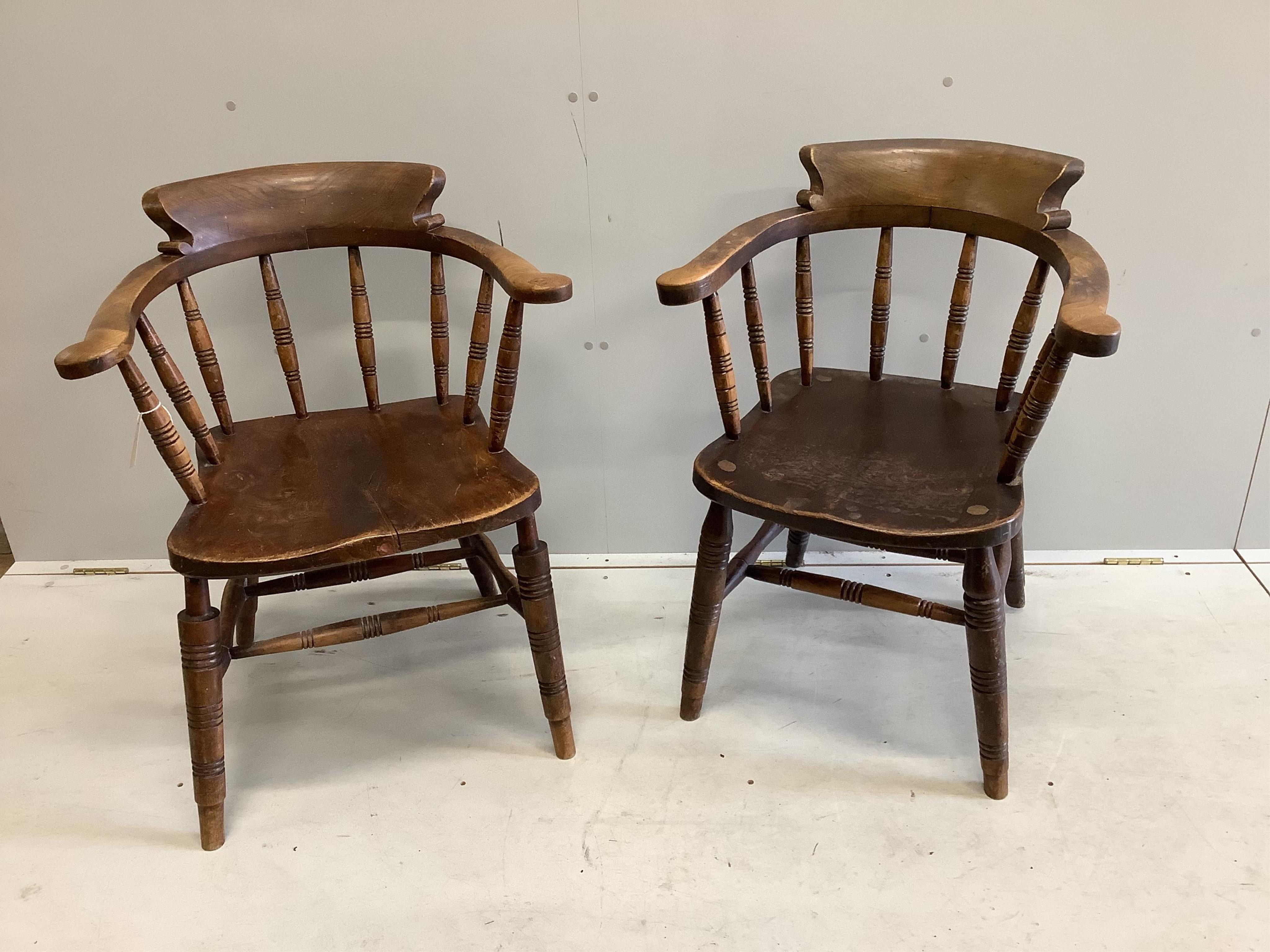 A pair of early 20th century elm and beech smokers bow chairs by Glenister, Wycombe, one bears Edward VII cypher, width 59cm, depth 48cm, height 84cm. Condition fair, one seat has cushion foam residue, the other split ve